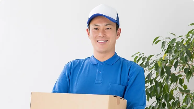 笑顔でダンボールを持つ運送業の男性